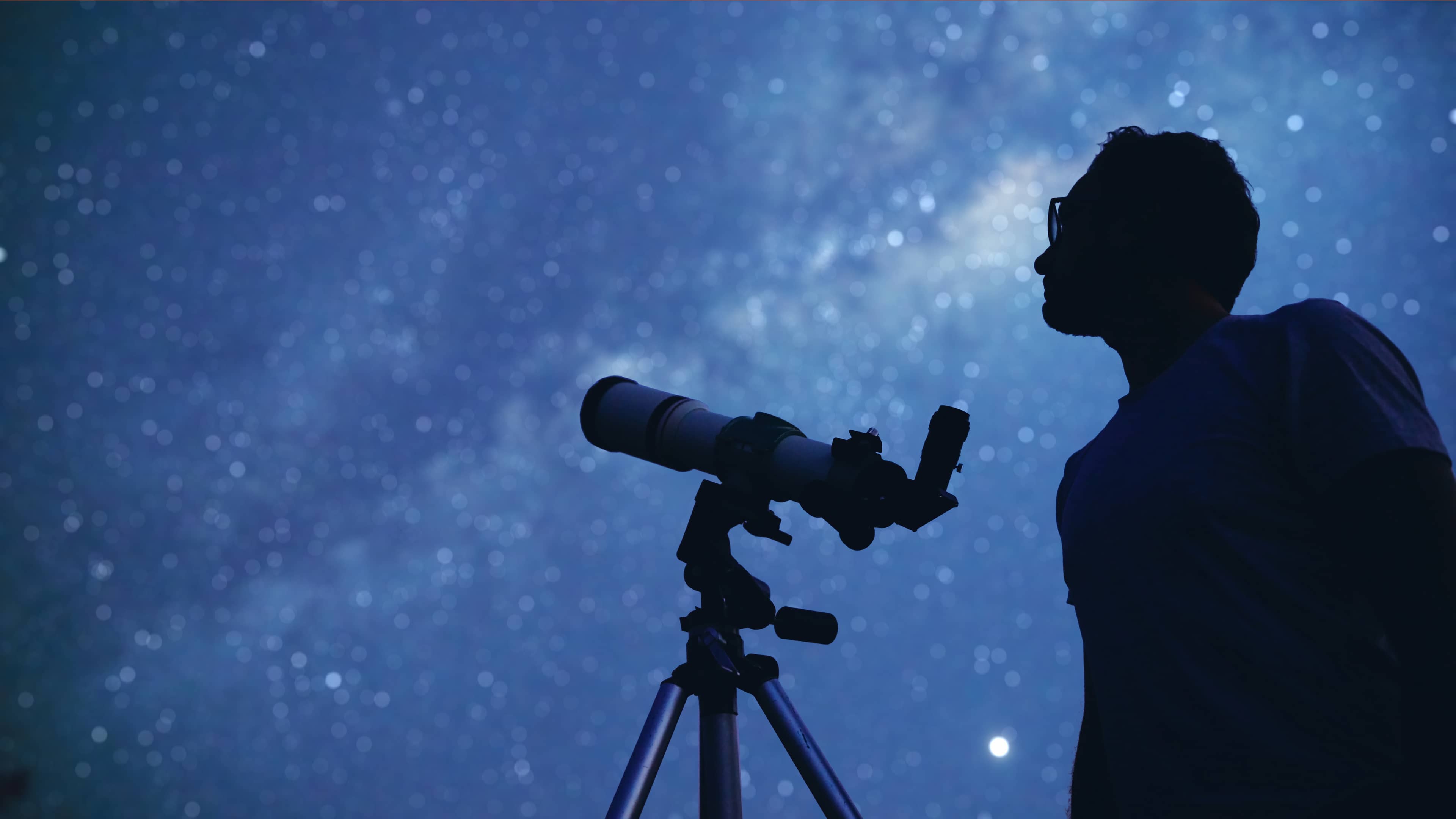 A Person looking at the night sky through a telescope